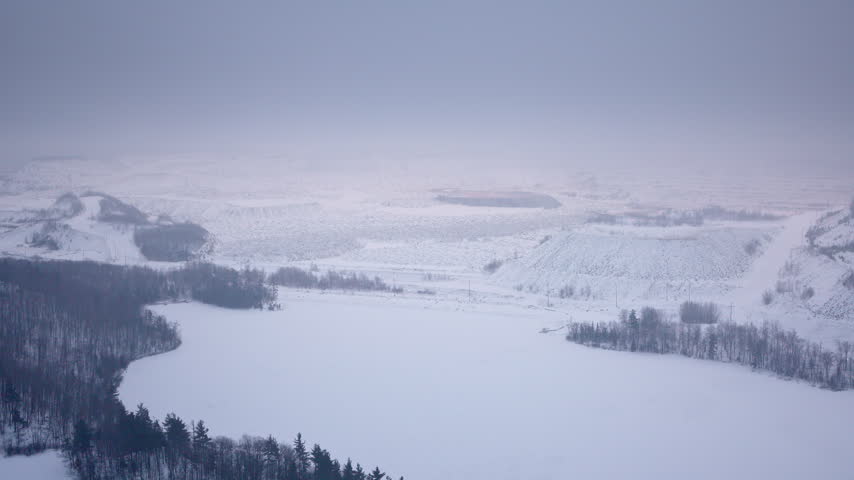 Cinematic drone shot overlooking large hills and a winter toboggan run in Northern Michigan