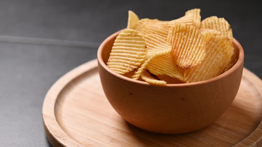 Bowl of potato chips rotating on black background