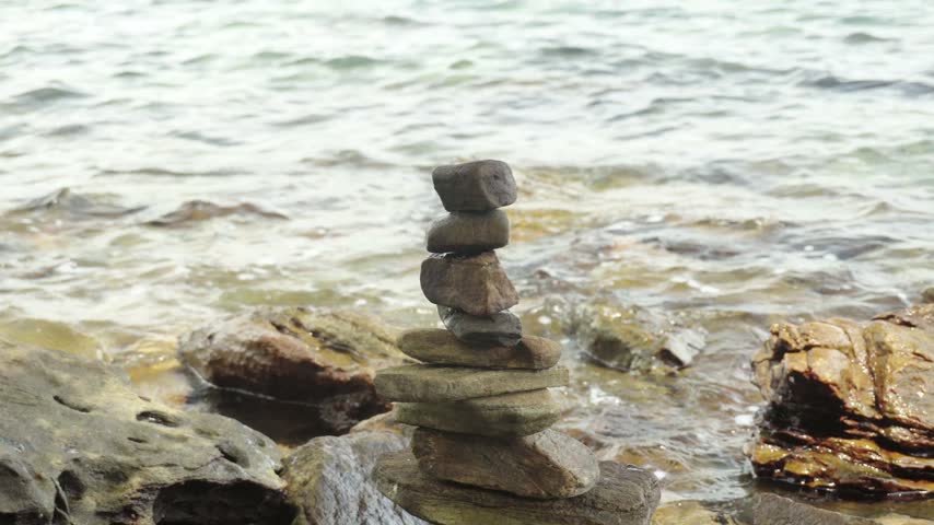 A moment of tranquility as gentle ocean waves wash up against the surrounding rock stack stones