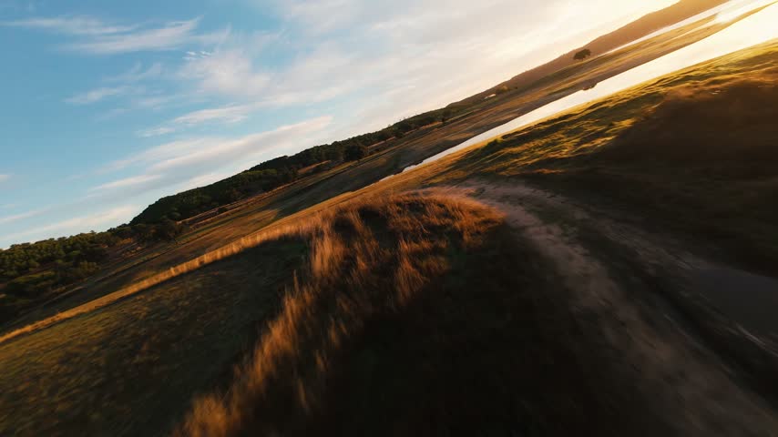 Golden light glides over mossy hills and calm waters. Sky