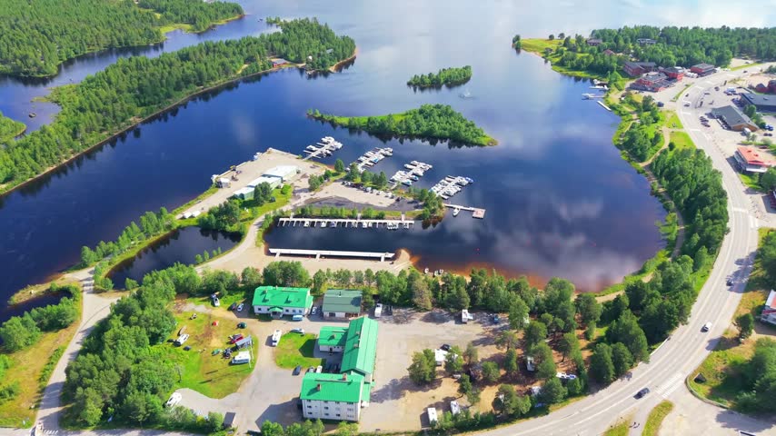 Aerial view of Lake Inari with marina, forested shoreline and buildings surrounded by dense pine woodland in Finnish Lapland, Northern Finland