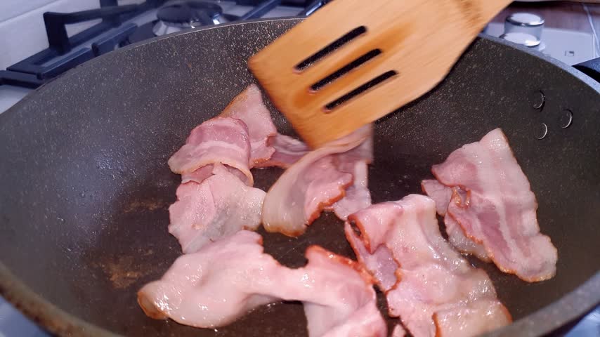 Bacon pieces frying in a pan. Illustration for food blogs and projects. Traditional breakfast. Appetizing meat in a frying pan.