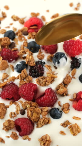 Breakfast Greek yogurt with granola and fresh berries scoop with spoon, close up. Healthy protein, fiber breakfast or snack
