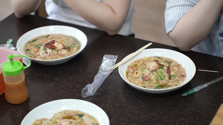 Asian seafood noodle dishes with shrimp, vegetables and savory gravy served on a restaurant table, featuring a casual dining experience.