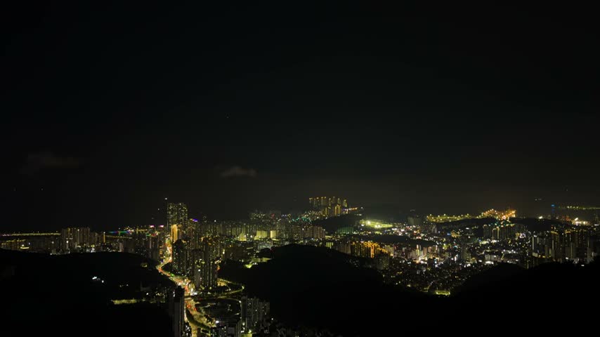 Time lapse, Breathtaking panoramic view of the busan city lights at night from the hwangnyeongsan mountain observatory, with traffic moving along roads
