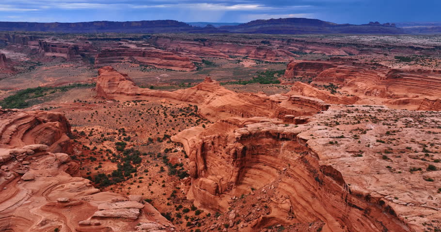 Breath-taking scenery of the desert with numerous canyons. Some shrubs grow in the scenery. The Arches National Park in Utah, USA. Aerial perspective.