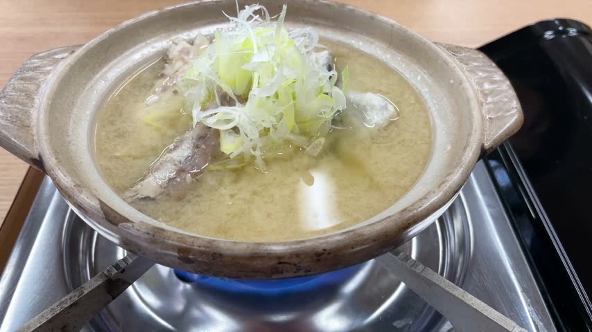 Fish bone soup served in an earthenware pot heated on a gas stove