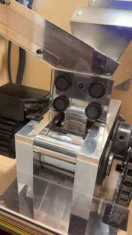 close-up of the internal stamping mechanism inside a coin-operated souvenir medal press machine at Sapporo TV Tower, Japan, showing the steel dies that press collectible medal designs