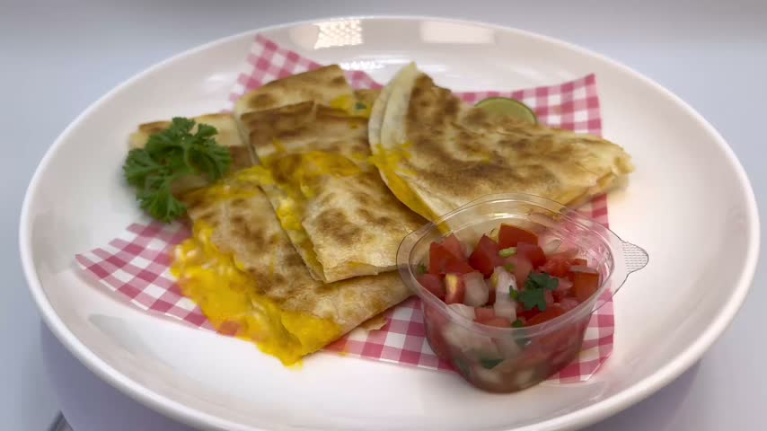 Close Up of Crispy Cheese Quesadilla with Tomato Salsa on White Plate