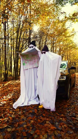 Two People in Halloween Ghost Costumes Walking Through Autumn Forest