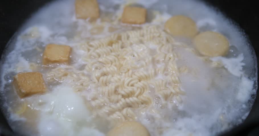 Close up of boiling instant noodles with fish tofu in hot soup pot