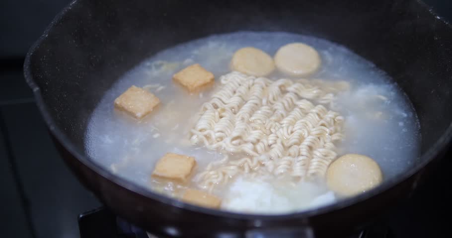 Close up of boiling instant noodles with fish tofu in hot soup pot