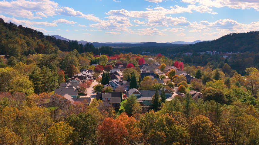 Quiet mountain neighborhood near Asheville featuring private homes surrounded by vibrant autumn foliage and rolling forested hills.