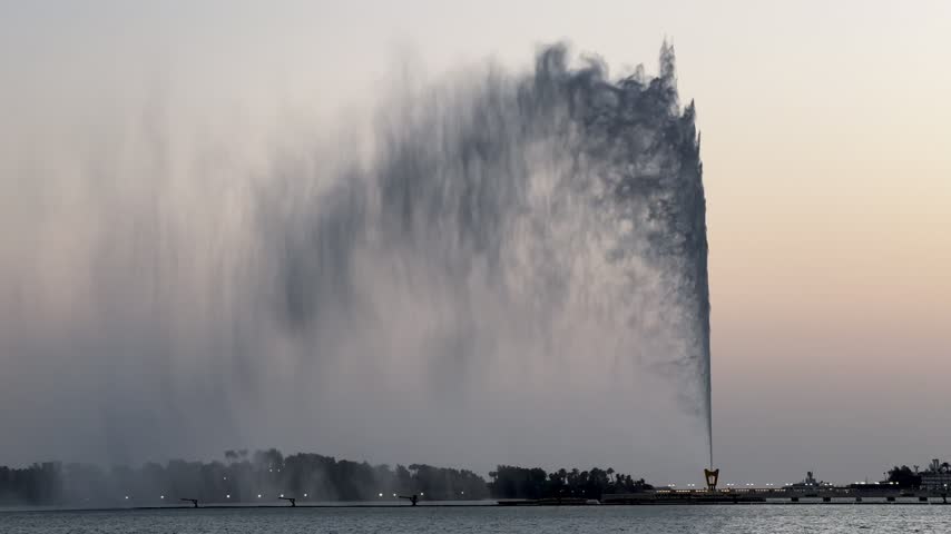 Close-up shot of King Fahd Fountain water jet shooting upward with soft mist against a twilight sky in Jeddah.