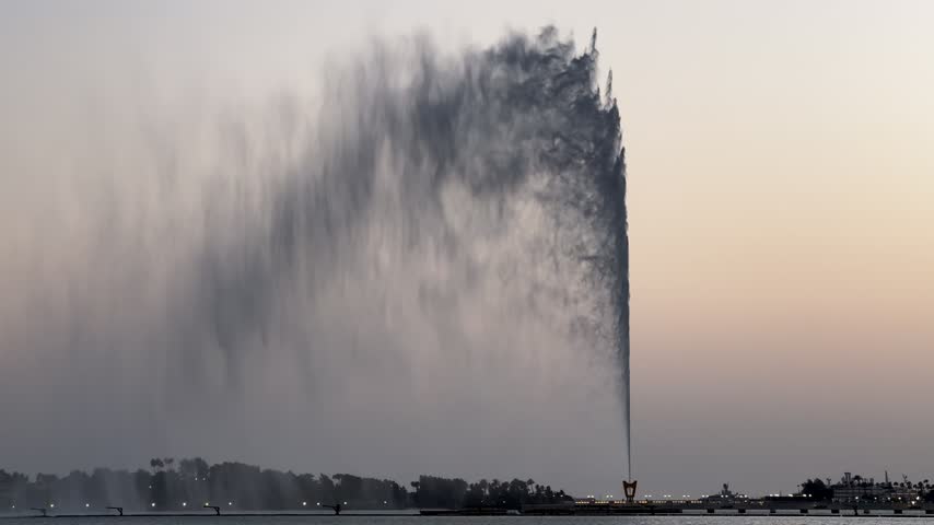Close-up shot of King Fahd Fountain water jet shooting upward with soft mist against a twilight sky in Jeddah.