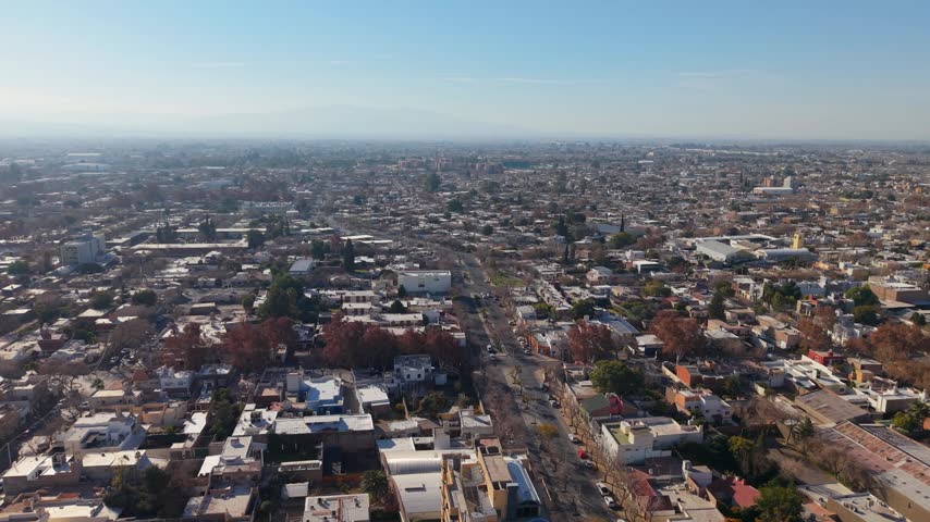 Vast and flat urban landscape of San Juan city under hazy afternoon sunlight. Static high-angle aerial view.
