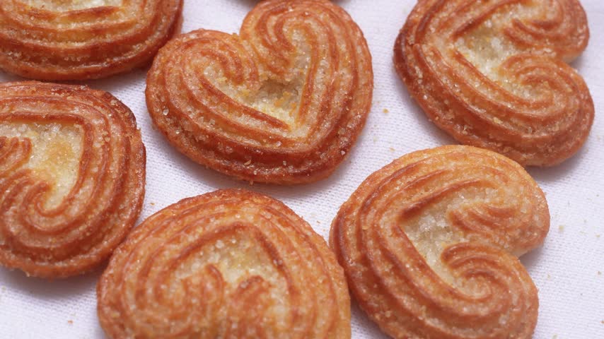 Selective focus tasty heart shaped sweet biscuits sprinkled with sugar granules caramel design, Little heart biscuits on a white background.