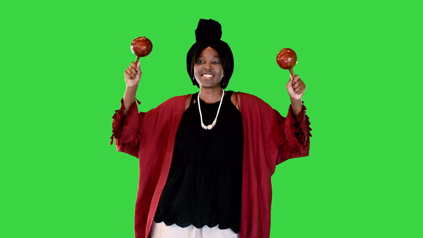 Very positive african american woman shakes maracas rhythmically on a Green Screen, Chroma Key.