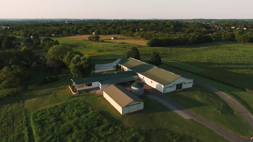 This shot captures a farm in Tennessee used as a wedding venue, with a beautiful white barn in the foreground and the rolling foliage of Tennessee in the background