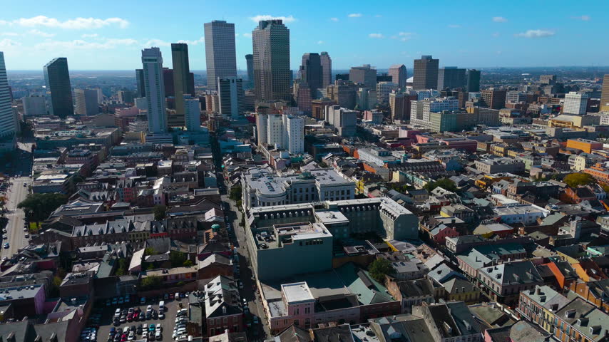 An aerial drone flight over historic French Quarter to the downtown New Orleans skyline on sunny day. Showcase the timeless charm and urban contrast of the Big Easy with this sweeping aerial drone shot panning over the historic French Quarter (Vieux Carré) toward the modern Downtown New Orleans skyline. Gliding high above classic Creole architecture, vibrant rooftops, and tree-lined streets, the camera smoothly reveals the towering skyscrapers of the Central Business District in the distance under a bright blue sky filled with puffy white summer clouds. Featuring flawless stabilization, vivid color reproduction, and crisp detail, this versatile clip is ideal for travel documentaries, tourism campaigns, real estate marketing, broadcast news bumpers, and cultural productions highlighting Louisiana