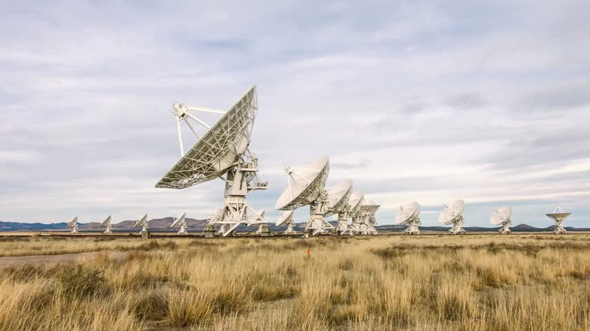 Large radio telescope dishes aligned in VLA observatory New Mexico desert landscape observing deep space signals under cloudy sky during daylight for advanced astronomical research and technology