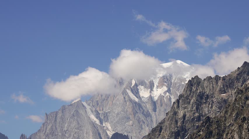 Video showcasing the spectacular scenery along the Tour du Mont Blanc, one of the most famous long distance trekking routes in the European Alps. The footage captures dramatic mountain peaks, snow covered summits, rugged ridges, glaciers, deep valleys, alpine meadows, and scenic trails surrounding the Mont Blanc massif. Changing weather and natural light create a constantly evolving atmosphere, revealing the impressive scale and beauty of the high mountain environment. The route passes through France, Italy, and Switzerland, offering diverse landscapes and exceptional panoramic views throughout the journey. This iconic trail attracts hikers, trekkers, backpackers, photographers, and outdoor enthusiasts from around the world. The video conveys a sense of exploration, adventure, freedom, and connection with nature while highlighting the remarkable scenery of the Alps. Suitable for travel documentaries, tourism promotion, hiking and trekking content, outdoor adventure, mountain landscapes, nature films, and scenic European travel footage.