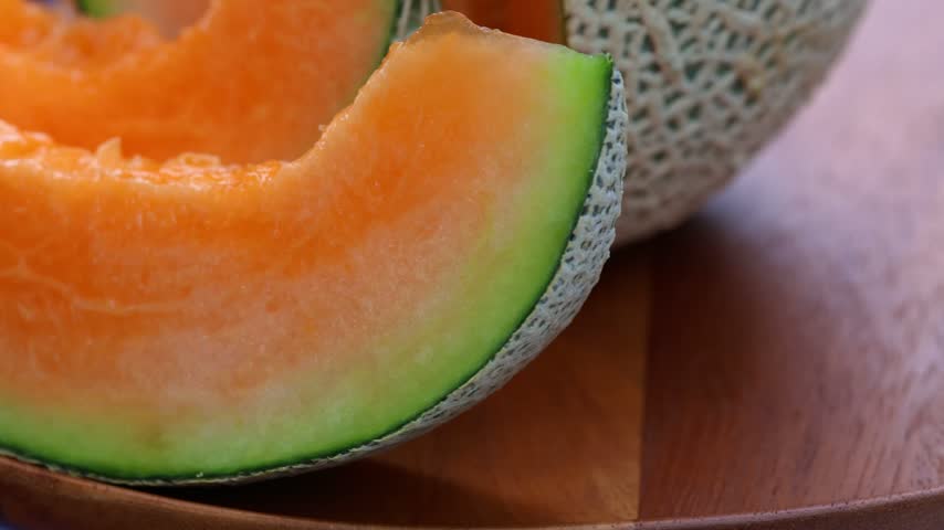 Fresh cantaloupe melon sliced on wooden