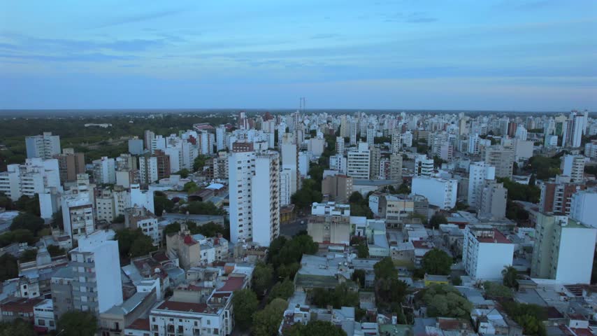 4K drone aerial view of La Plata, Buenos Aires, Argentina at sunset. Urban skyline, buildings and streets illuminated by warm evening light across the city.