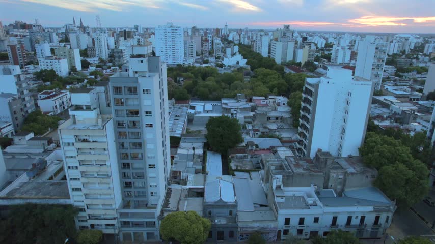 4K drone aerial view of La Plata, Buenos Aires, Argentina at sunset. Urban skyline, buildings and streets illuminated by warm evening light across the city.