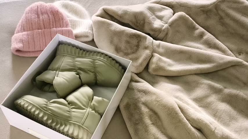 The woman is preparing winter and autumn clothing for the upcoming cold weather. coat and hats, preparing seasonal footwear and outerwear for winter and autumn.