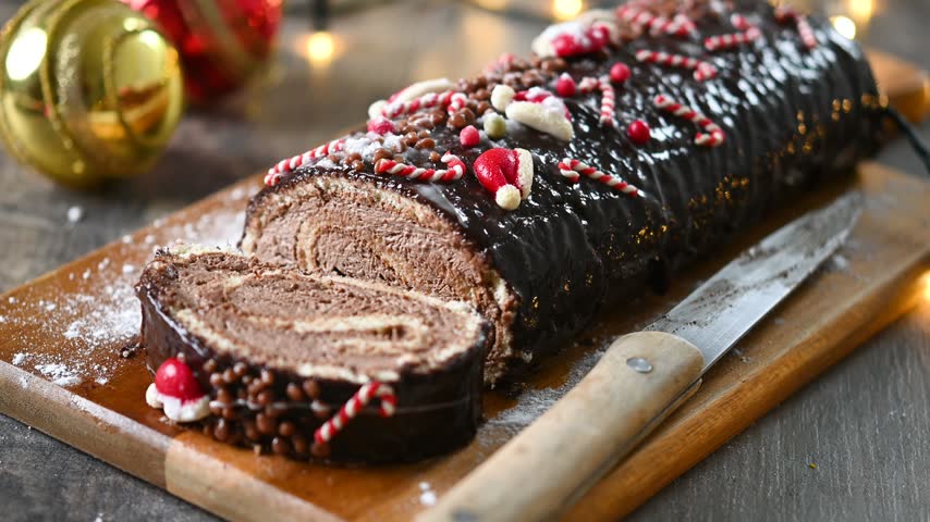 Christmas chocolate yule log cake with festive decorations on wooden table