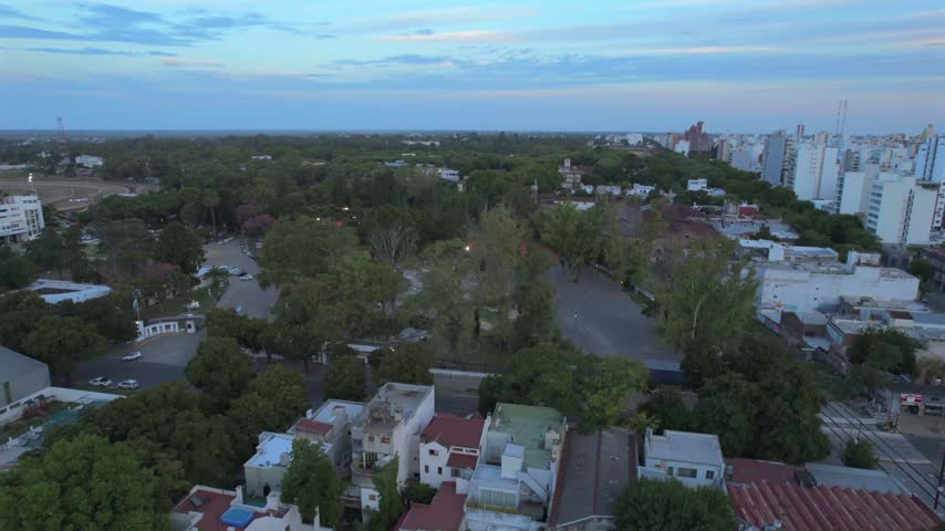 4K drone aerial view of La Plata, Buenos Aires, Argentina at sunset. Urban skyline, buildings and streets illuminated by warm evening light across the city.