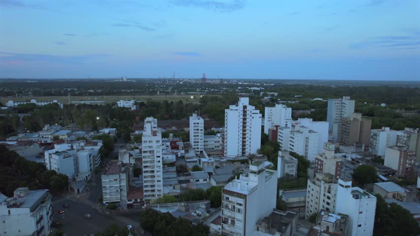 4K drone aerial view of La Plata, Buenos Aires, Argentina at sunset. Urban skyline, buildings and streets illuminated by warm evening light across the city.
