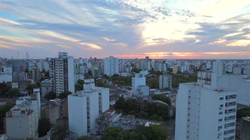 4K drone aerial view of La Plata, Buenos Aires, Argentina at sunset. Urban skyline, buildings and streets illuminated by warm evening light across the city.