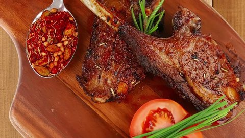 meat on wooden plate : roast ribs on wood with tomatoes chives and dry spices 1920x1080 intro motion slow hidef hd