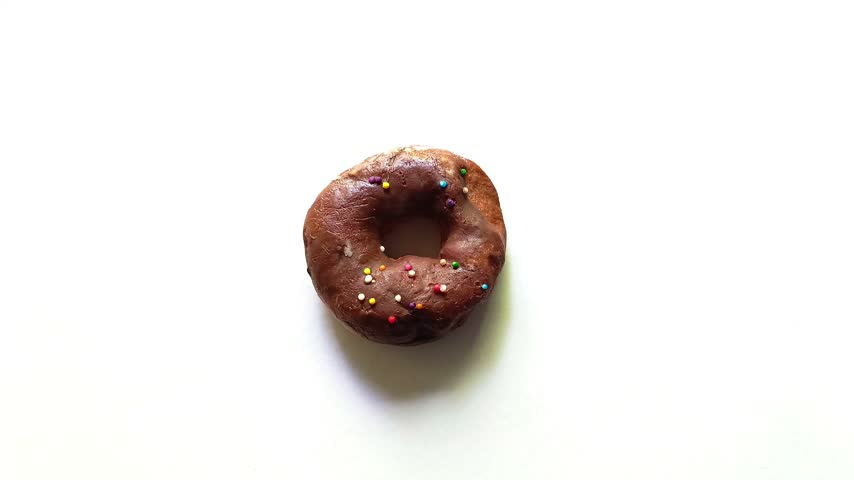 Overhead view of single sweet chocolate glazed donut topped with colorful round sprinkles isolated on clean white background