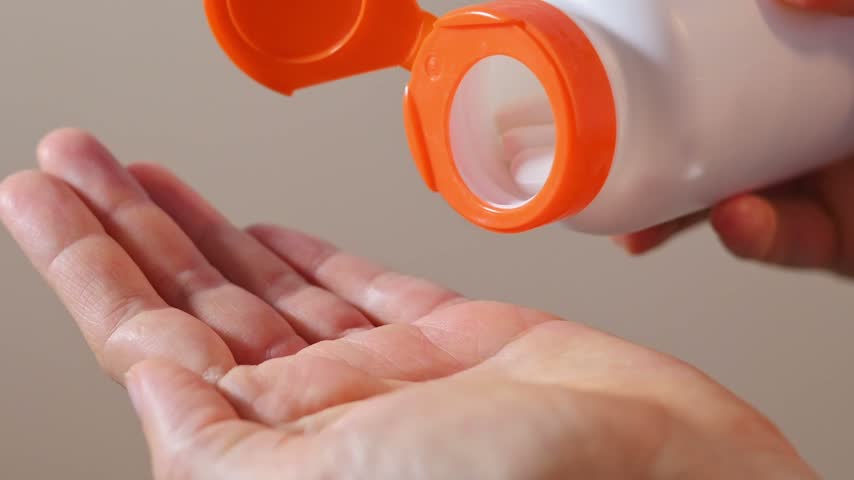 White container releases pills into woman palm, illustrating supplement intake for wellness communication. Vitamin support, nutrition care, and dietary routines suit lifestyle education and marketing