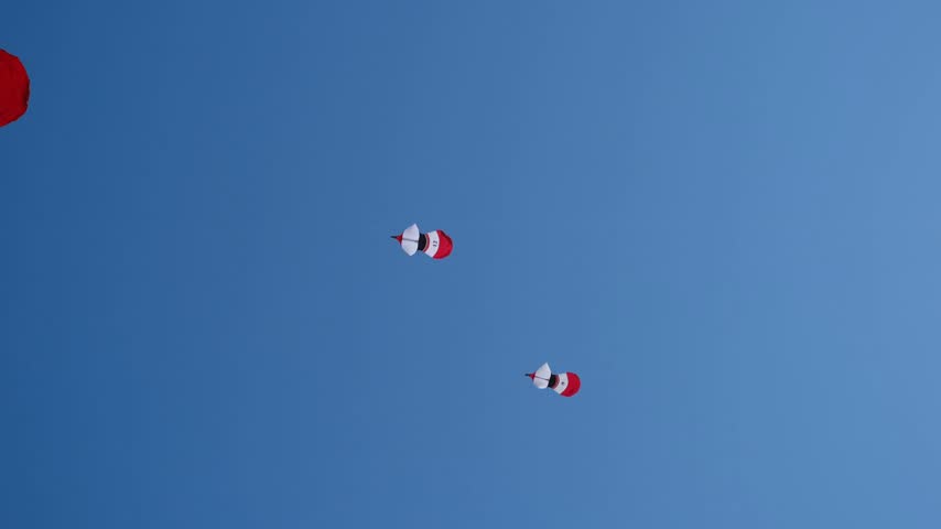 Many Colorful Kites Flying in a Blue Sky on Taut Strings Shimmering in Sunlight During an Annual Kite Festival, 4K 50fps