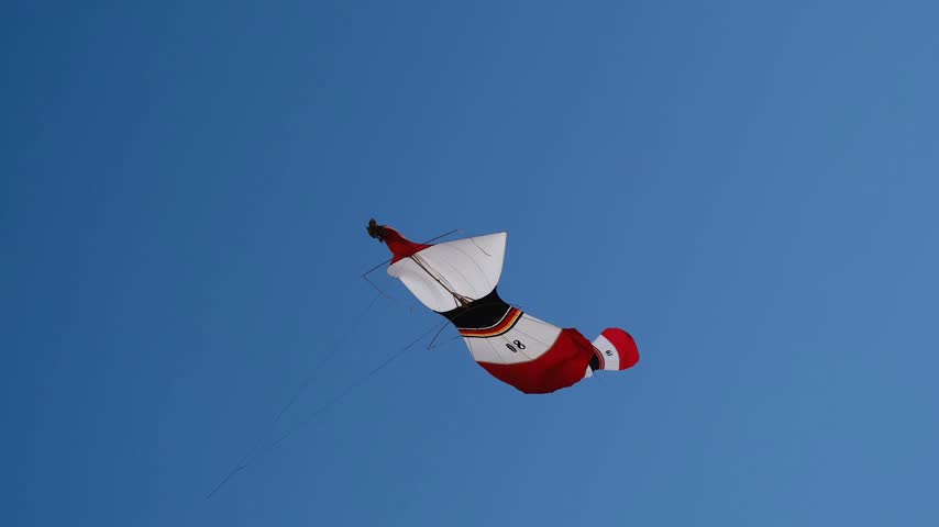 Many Colorful Kites Flying in a Blue Sky on Taut Strings Shimmering in Sunlight During an Annual Kite Festival, 4K 50fps