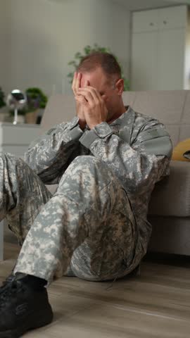 Depressed soldier in camouflage crying at home