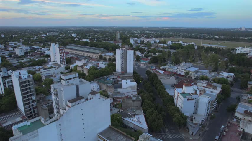 4K drone aerial view of La Plata, Buenos Aires, Argentina at sunset. Urban skyline, buildings and streets illuminated by warm evening light across the city.