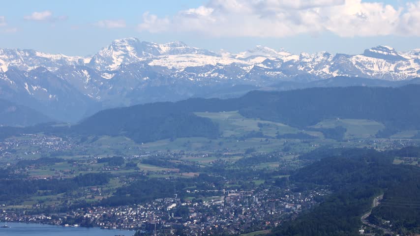 View of Uetliberg overlooking the city of Zurich, green hills, and the snow-capped Alps in the distance in Zurich, Zurich, Switzerland.