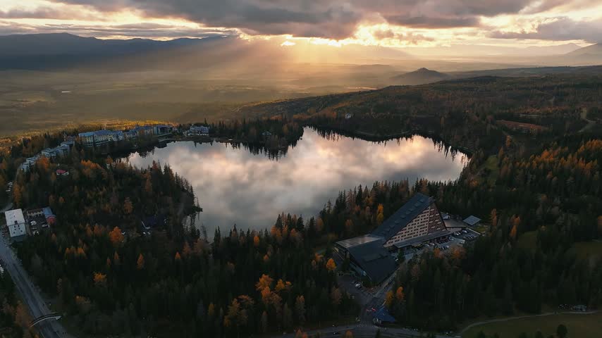 Strbske Lake, Slovakia - 4K Aerial view of the beautiful Strbske Lake (Strbske Pleso) at sunset with autumn foliage and warm sunlight and clouds