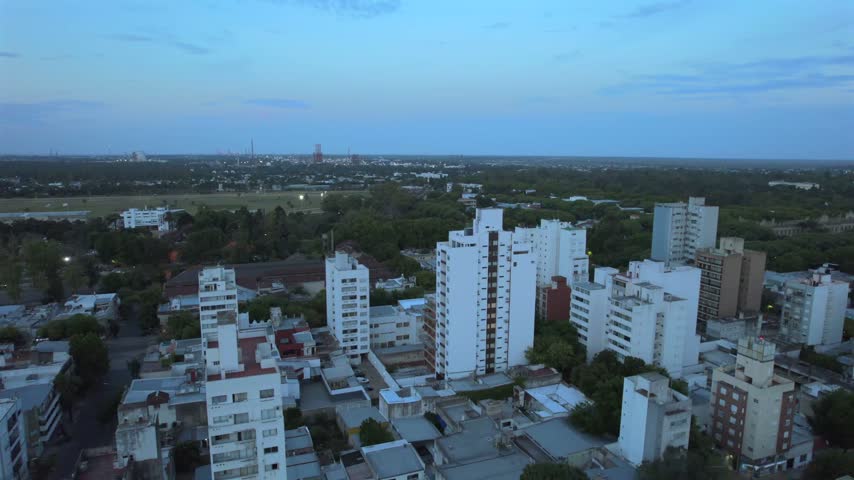 4K drone aerial view of La Plata, Buenos Aires, Argentina at sunset. Urban skyline, buildings and streets illuminated by warm evening light across the city.