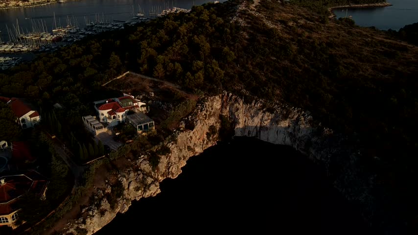 Dragons Eye Lake in Rogoznica, Croatia sits within rocky coast beside marina, aerial establishing descend with harbor in backdrop