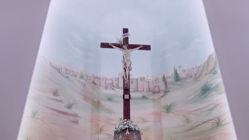 Wooden crucifix mounted over a painted mural of Jerusalem hills inside a church apse