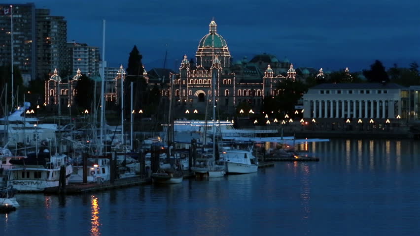 VICTORIA BC CANADA MAY 2013: Parliament Buildings is home to the Legislative Assembly of British Columbia. Economic stimulus cruise ship tourism. People exploring the city. Night over marina.
