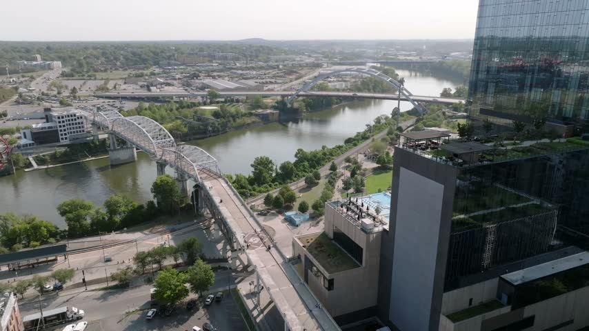 Drone aerial video capturing park and green space around Ascend Amphitheater and the walking bridge into downtown Nashville, Tennessee