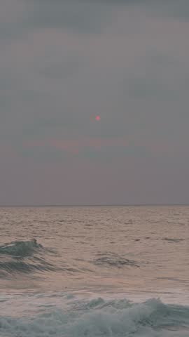 surf The pink sun slowly setting behind clouds over the ocean horizon in puerto escondido, mexico