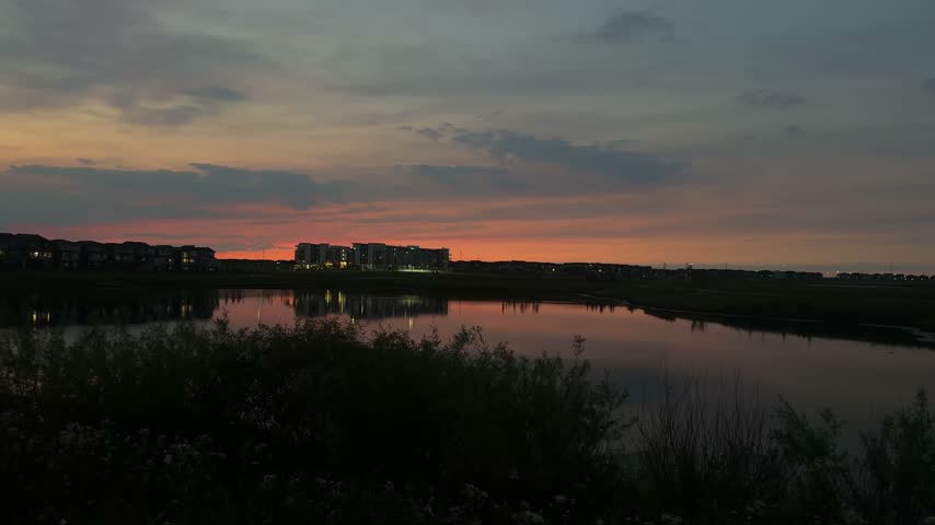 Apartment building next to a pond in the evening sunset wide
